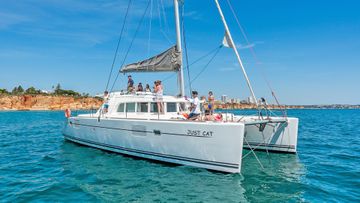 Lagoon 440 catamaran sailing through turquoise Gulf of Mexico water with dolphins leaping alongside