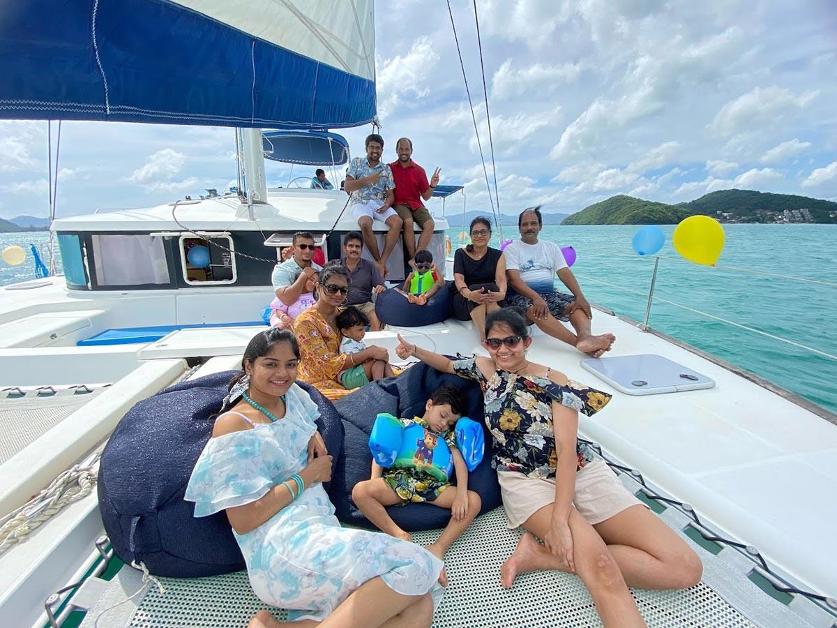 Group of guests dining on the aft deck of the Lagoon 440 with a seafood spread and rosé, turquoise water behind